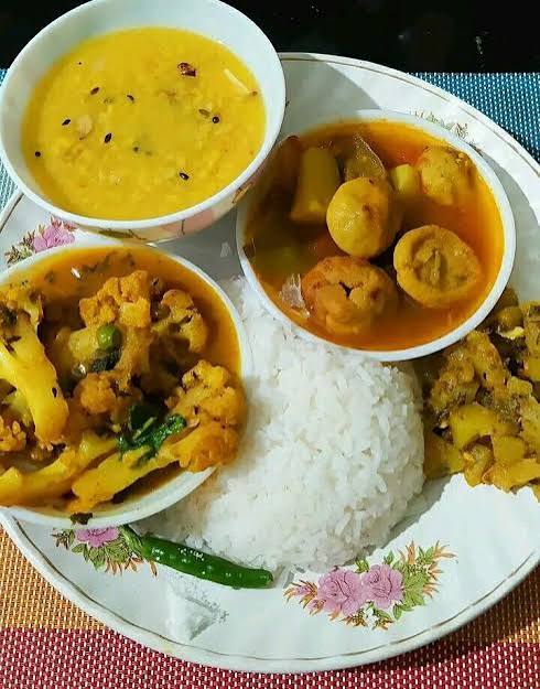Egg curry meal with rice, dal, vegetables, and home-style side dishes